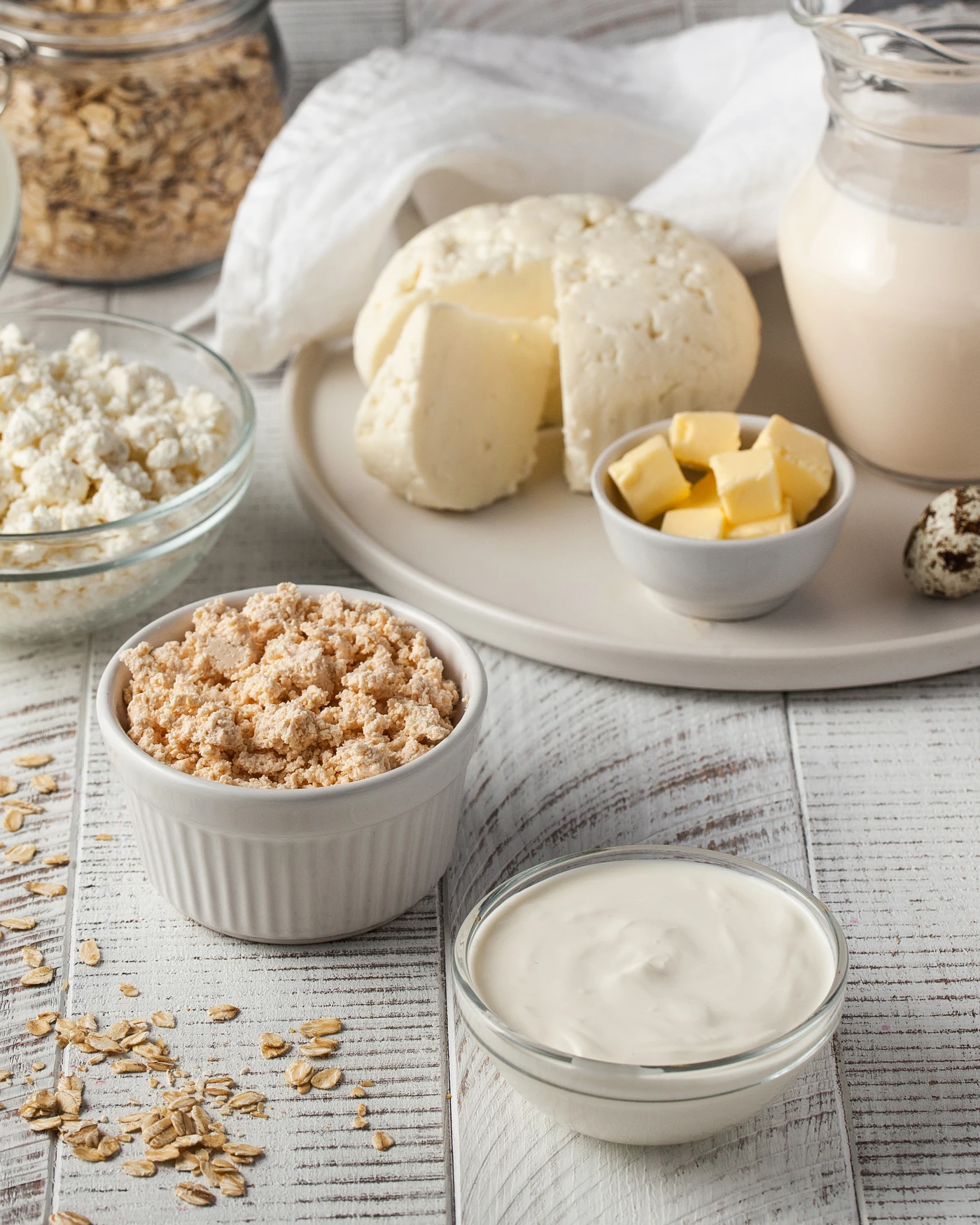 Lácteos artesanales y cereales sobre fondo de madera blanca